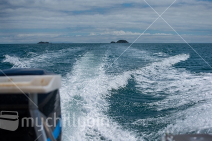 Wake from moving boat looking back to receding islands in the Hauraki Gulf, Auckland.